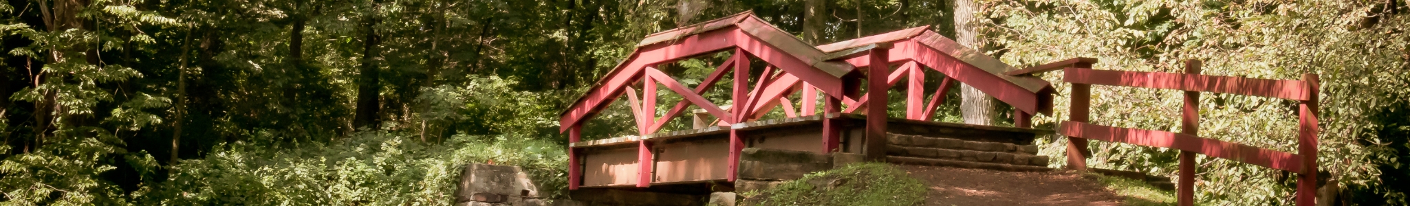 Summer at Washington Crossing, Pennsylvania. Red wooden bridge with lush leaves.