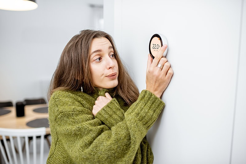 Why Is My Heat Pump Turning On and Off Frequently? A lady turning up the temperature.